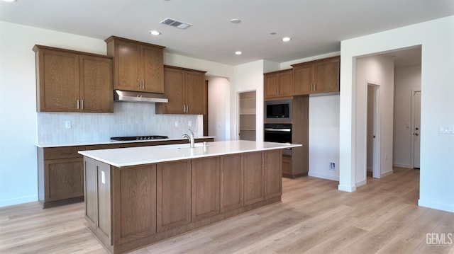 16903 Mairs Dr, Bakersfield, CA 93314 - kitchen with stainless steel microwave, under cabinet range hood, gas stovetop, a kitchen island with sink, and oven