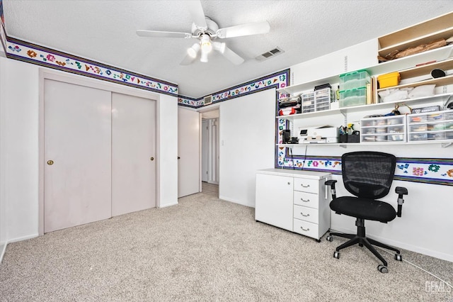 office featuring visible vents, ceiling fan, light carpet, and a textured ceiling