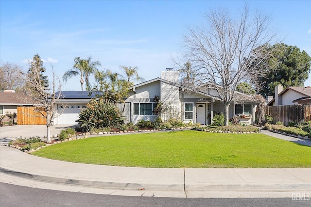 mid-century home with a garage, fence, solar panels, and a front yard