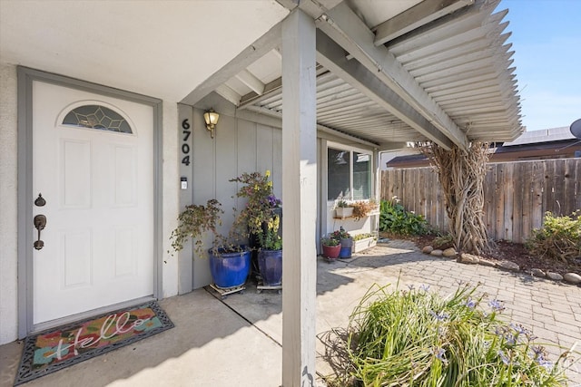 entrance to property with a patio area, fence, and stucco siding