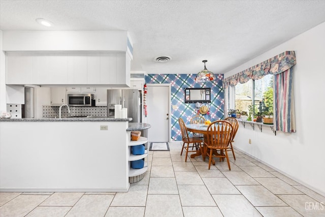 dining space featuring light tile patterned floors, wallpapered walls, visible vents, and a textured ceiling