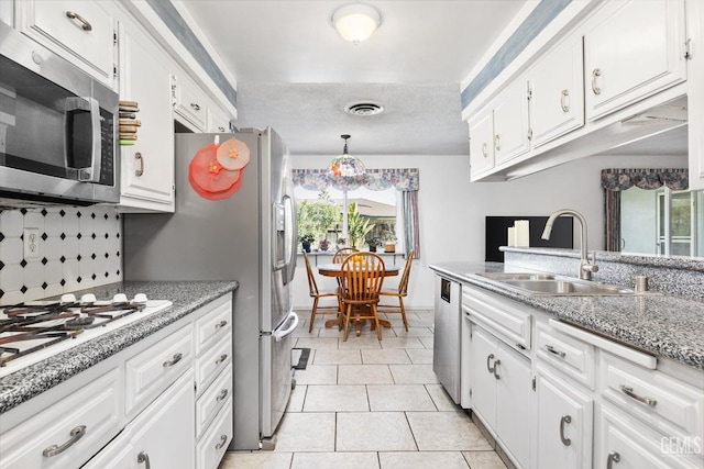 kitchen with light tile patterned floors, stainless steel appliances, a sink, visible vents, and white cabinets