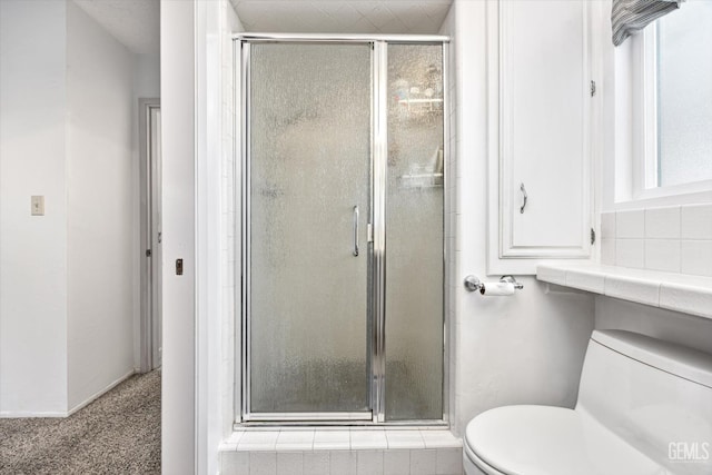 bathroom featuring a stall shower and toilet