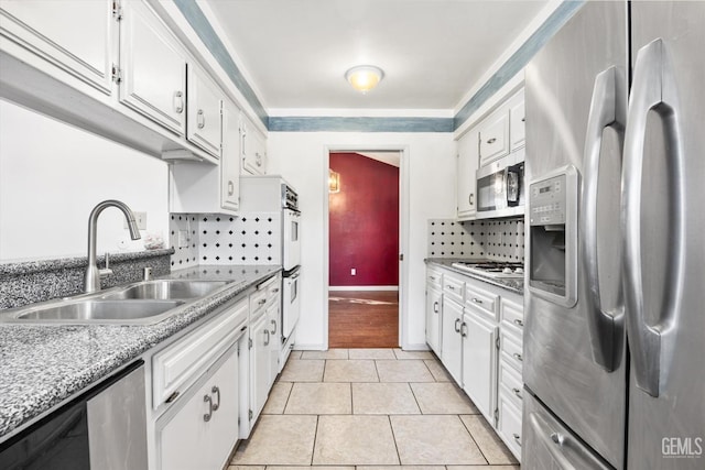 kitchen with light tile patterned flooring, stainless steel appliances, a sink, white cabinetry, and light countertops