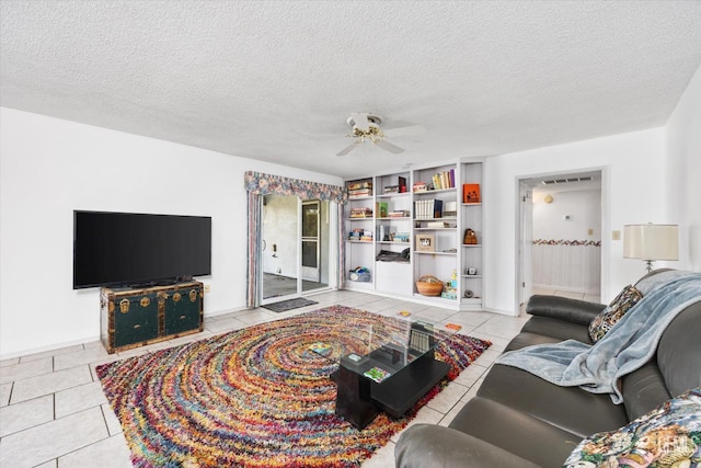 living room with a textured ceiling, visible vents, a ceiling fan, and tile patterned floors