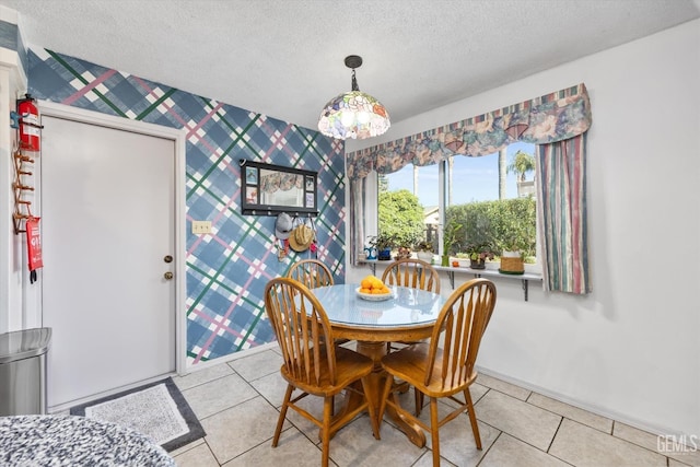 dining area with light tile patterned floors, a textured ceiling, baseboards, and wallpapered walls