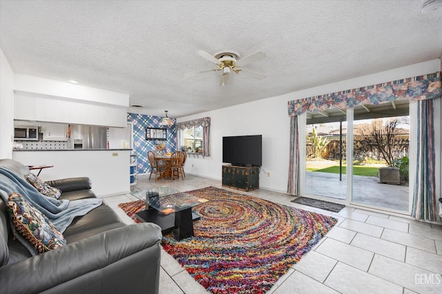 living area with a ceiling fan, a textured ceiling, and light tile patterned floors