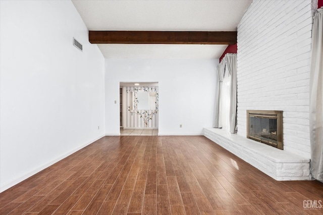 unfurnished living room featuring baseboards, visible vents, wood finished floors, a fireplace, and beam ceiling