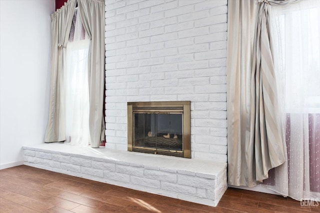 room details with a brick fireplace, baseboards, and wood finished floors