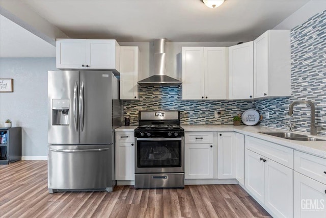 kitchen with wall chimney range hood, stainless steel appliances, sink, and white cabinets