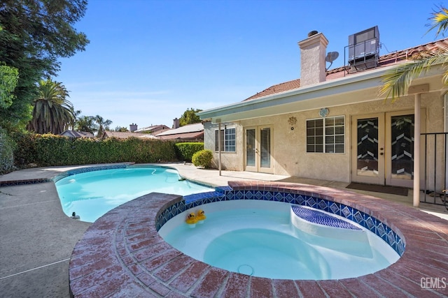 view of swimming pool with an in ground hot tub, a patio, and french doors