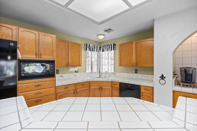 kitchen with sink, tile counters, and black appliances