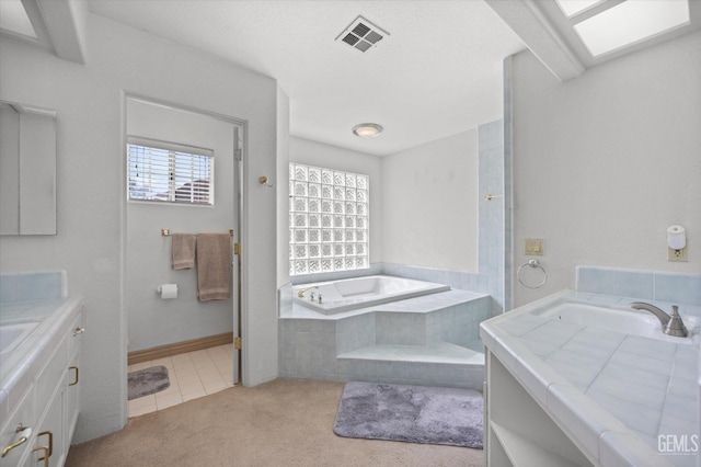 bathroom with tile patterned floors, vanity, and tiled bath