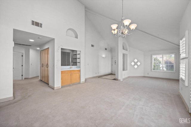 unfurnished living room featuring light carpet, high vaulted ceiling, and a chandelier