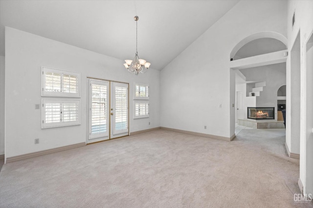 unfurnished room featuring light carpet, a fireplace, high vaulted ceiling, and french doors