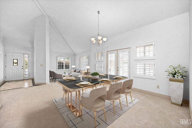 carpeted dining room with high vaulted ceiling, a healthy amount of sunlight, and an inviting chandelier