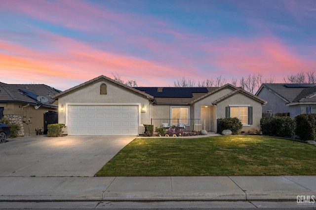 ranch-style home featuring concrete driveway, an attached garage, roof mounted solar panels, a front lawn, and stucco siding