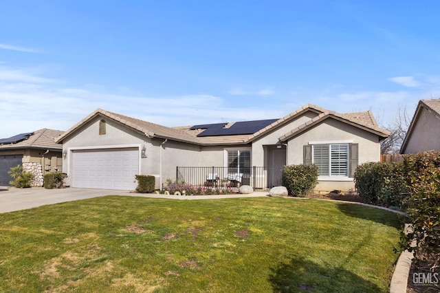 single story home featuring stucco siding, concrete driveway, roof mounted solar panels, a garage, and a front lawn