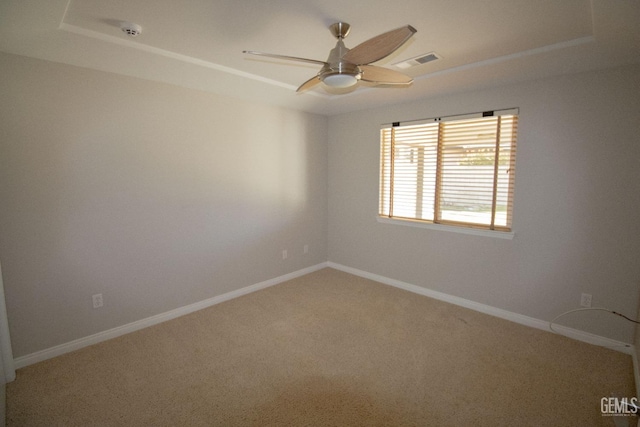 carpeted spare room featuring ceiling fan and a tray ceiling