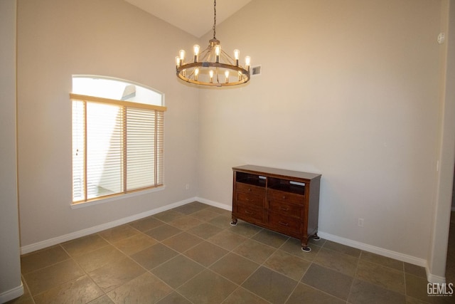 spare room with high vaulted ceiling and an inviting chandelier