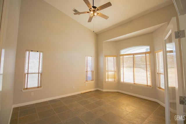 unfurnished room with ceiling fan, dark tile patterned floors, and high vaulted ceiling