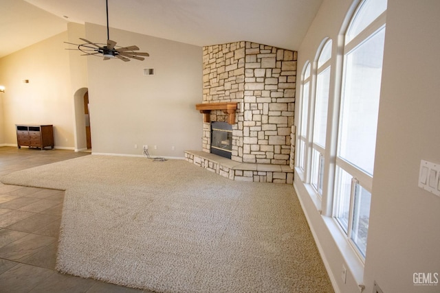 unfurnished living room with ceiling fan, carpet, vaulted ceiling, and a fireplace