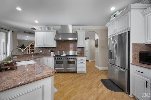 214 Driver Rd, Bakersfield, CA 93314 - kitchen with appliances with stainless steel finishes, wall chimney exhaust hood, a sink, decorative backsplash, and arched walkways