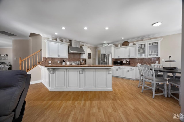 214 Driver Rd, Bakersfield, CA 93314 - kitchen with stainless steel fridge, wall chimney exhaust hood, a peninsula, ornamental molding, and tasteful backsplash