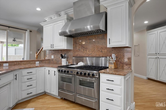 214 Driver Rd, Bakersfield, CA 93314 - kitchen with wall chimney range hood, double oven range, ornamental molding, light wood-style floors, and white cabinetry
