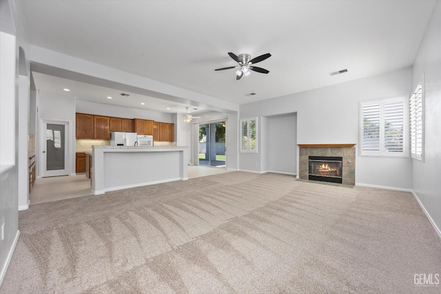 unfurnished living room featuring visible vents, a ceiling fan, light carpet, and a fireplace