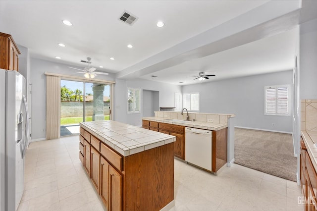 kitchen featuring dishwasher, a center island, a ceiling fan, and refrigerator with ice dispenser