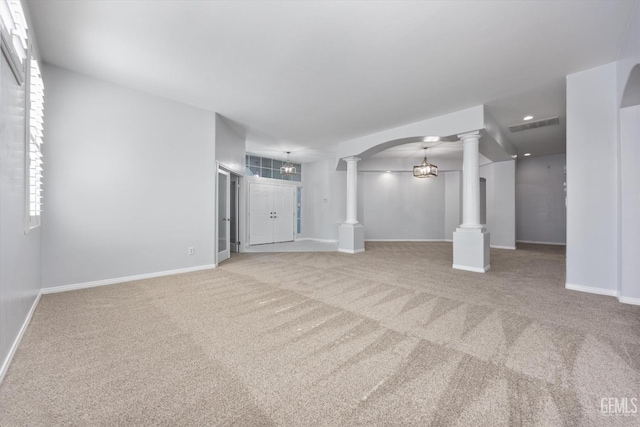 unfurnished living room featuring visible vents, baseboards, decorative columns, and carpet