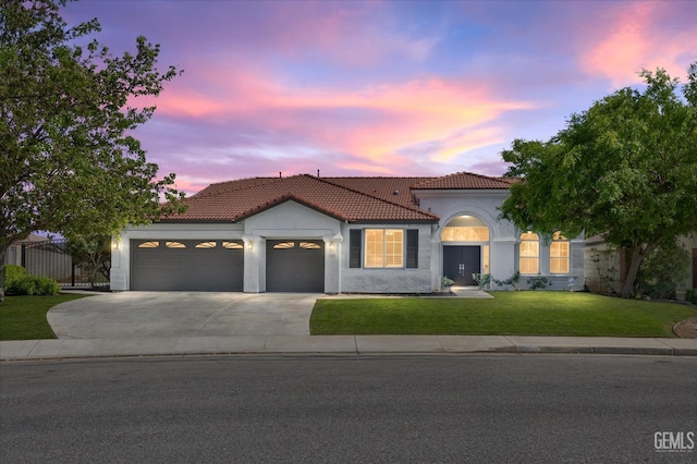 mediterranean / spanish home with a tiled roof, a garage, fence, concrete driveway, and a front lawn