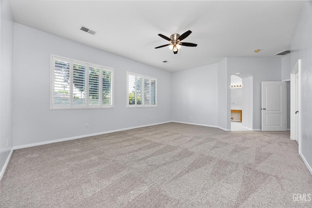 spare room with arched walkways, carpet flooring, visible vents, and a ceiling fan