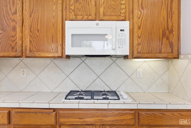 kitchen featuring brown cabinets, light countertops, white appliances, and decorative backsplash