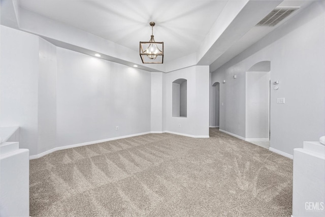 empty room with baseboards, a chandelier, carpet flooring, visible vents, and arched walkways