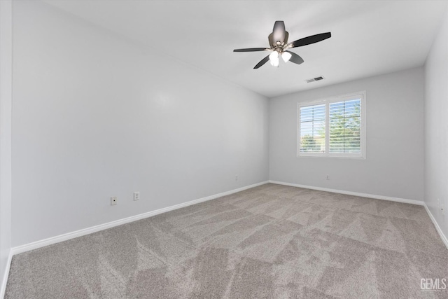 carpeted spare room featuring ceiling fan, baseboards, and visible vents