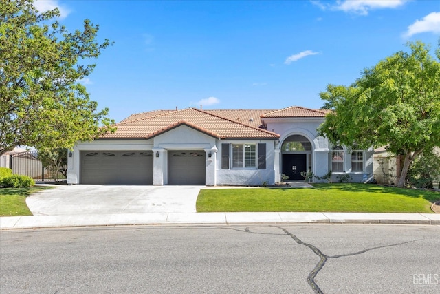 mediterranean / spanish home featuring stucco siding, driveway, a front yard, a tile roof, and a garage