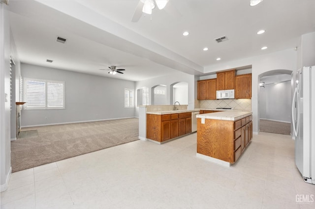 kitchen with arched walkways, a ceiling fan, white appliances, and light carpet