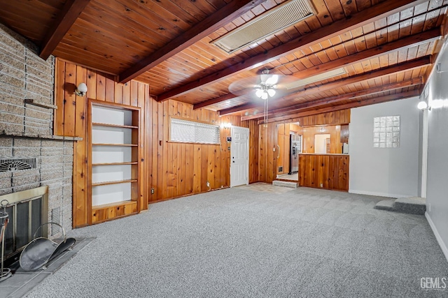 unfurnished living room with wood ceiling, a fireplace, wooden walls, and beamed ceiling