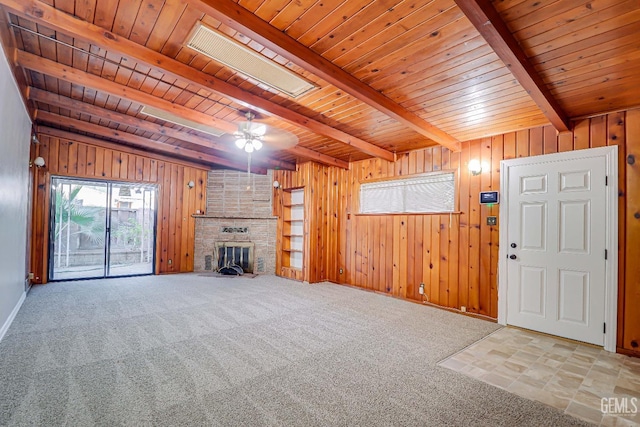 unfurnished living room featuring wooden walls, beam ceiling, and a fireplace