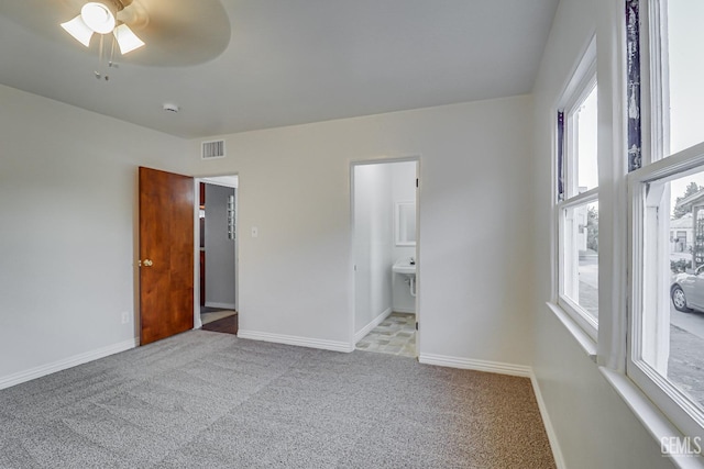 unfurnished bedroom featuring ensuite bathroom, light colored carpet, and ceiling fan