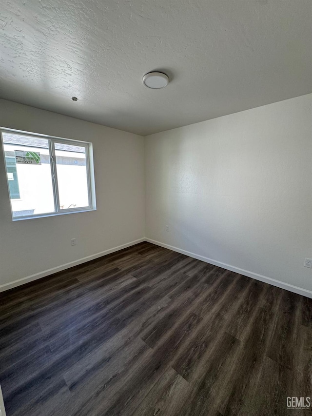 empty room featuring dark wood finished floors, baseboards, and a textured ceiling