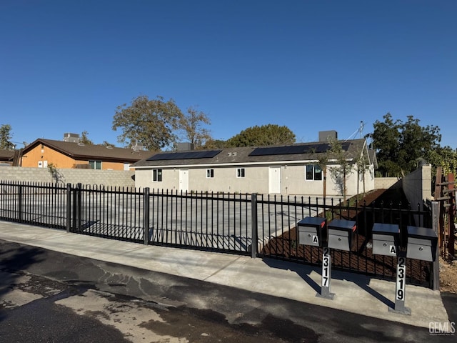 view of front of home featuring solar panels, a gate, and a fenced front yard