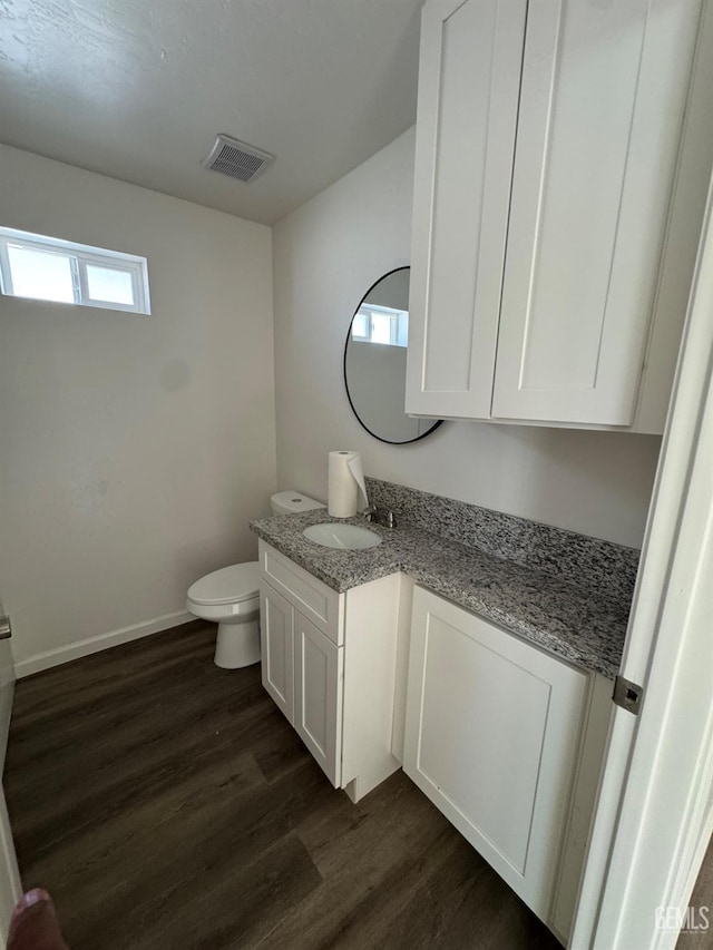 bathroom featuring visible vents, toilet, wood finished floors, baseboards, and vanity