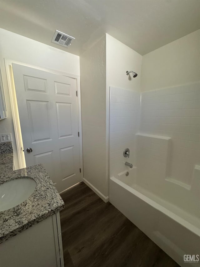 bathroom featuring vanity, washtub / shower combination, wood finished floors, and visible vents