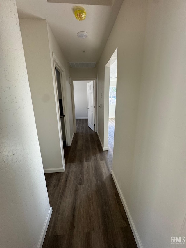 hallway with dark wood-type flooring and baseboards