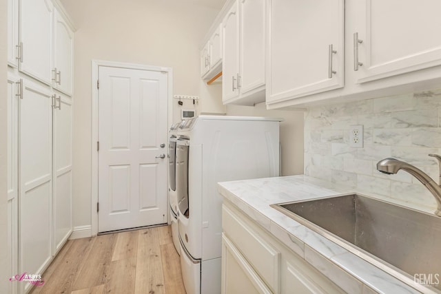 washroom featuring cabinets, separate washer and dryer, sink, and light hardwood / wood-style flooring