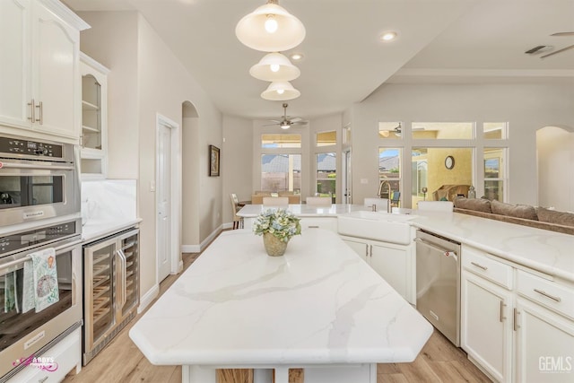 kitchen with white cabinetry, sink, wine cooler, hanging light fixtures, and stainless steel appliances