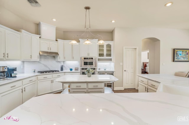 kitchen with white cabinetry, hanging light fixtures, light stone countertops, and appliances with stainless steel finishes